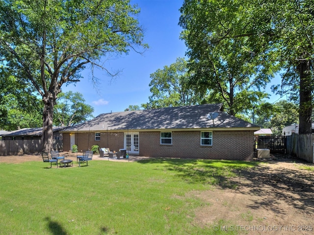3609 Dana Dr, Bartlesville, OK 74006 - back of house featuring french doors, a fenced backyard, brick siding, and a fire pit