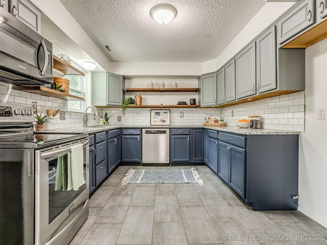 3609 Dana Dr, Bartlesville, OK 74006 - kitchen with stainless steel appliances, open shelves, a textured ceiling, light stone countertops, and tasteful backsplash