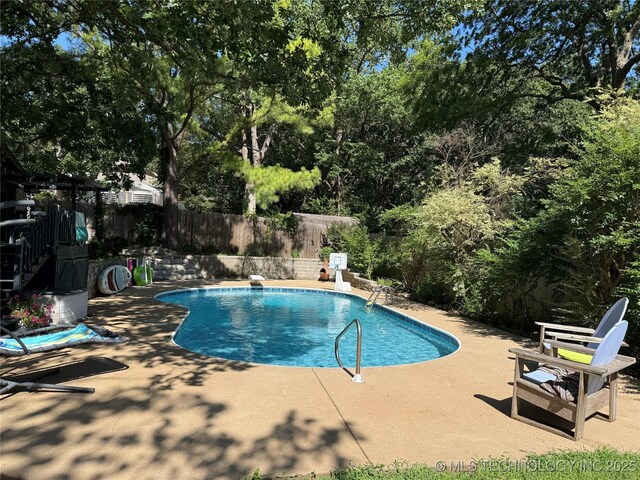 2501 Cherokee Hills Pl, Bartlesville, OK 74006 - view of pool with a fenced backyard, a patio area, view of wooded area, and a diving board