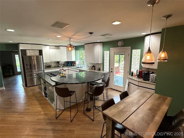 2501 Cherokee Hills Pl, Bartlesville, OK 74006 - kitchen featuring stainless steel fridge with ice dispenser, recessed lighting, white cabinetry, a kitchen bar, and a center island