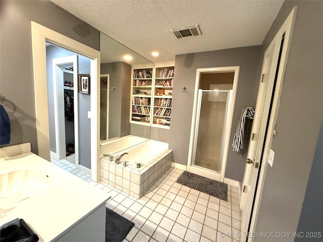 2501 Cherokee Hills Pl, Bartlesville, OK 74006 - bathroom with a stall shower, a bath, a textured ceiling, a spacious closet, and vanity