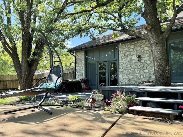 2501 Cherokee Hills Pl, Bartlesville, OK 74006 - back of property featuring stone siding, a patio area, roof with shingles, and board and batten siding