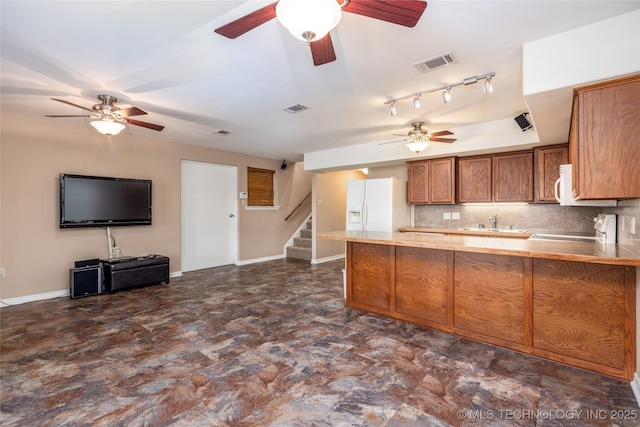 609 Lakeshore Dr, Durant, OK 74701 - kitchen featuring a ceiling fan, brown cabinetry, white appliances, a peninsula, and tasteful backsplash