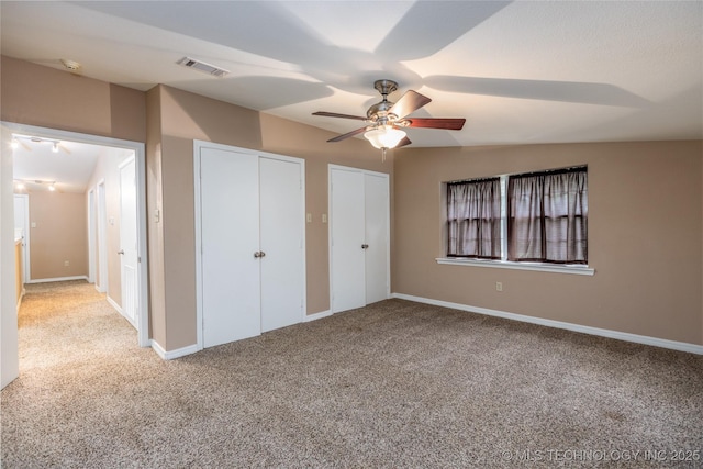 609 Lakeshore Dr, Durant, OK 74701 - unfurnished bedroom featuring light carpet, ceiling fan, and two closets