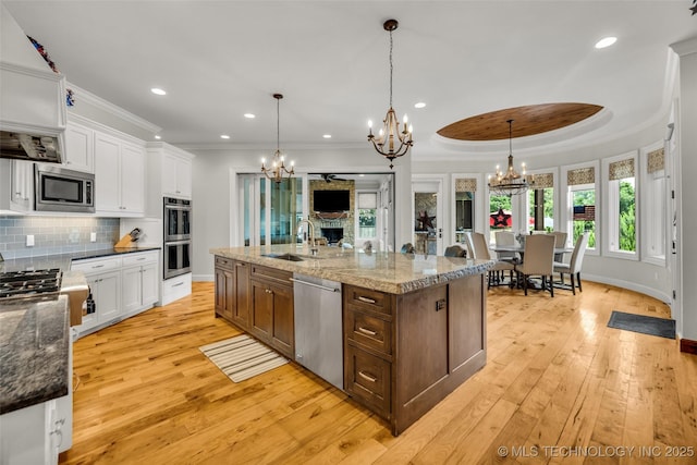 13533 S Lewis Ave, Bixby, OK 74008 - kitchen with appliances with stainless steel finishes, a chandelier, white cabinets, light wood-style floors, and crown molding