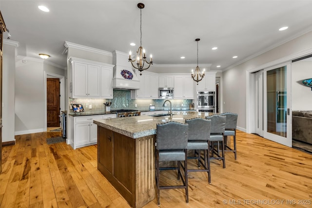 13533 S Lewis Ave, Bixby, OK 74008 - kitchen with appliances with stainless steel finishes, custom exhaust hood, a chandelier, ornamental molding, and an island with sink