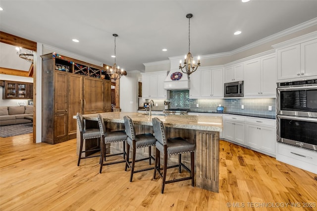 13533 S Lewis Ave, Bixby, OK 74008 - kitchen with appliances with stainless steel finishes, a chandelier, ornamental molding, backsplash, and a breakfast bar area