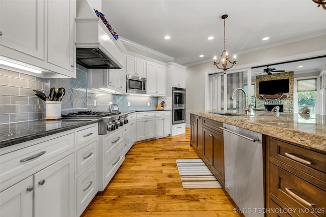 13533 S Lewis Ave, Bixby, OK 74008 - kitchen featuring stainless steel appliances, a ceiling fan, premium range hood, crown molding, and light wood-style flooring