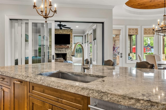 13533 S Lewis Ave, Bixby, OK 74008 - kitchen with a chandelier, brown cabinets, light stone countertops, ornamental molding, and a fireplace