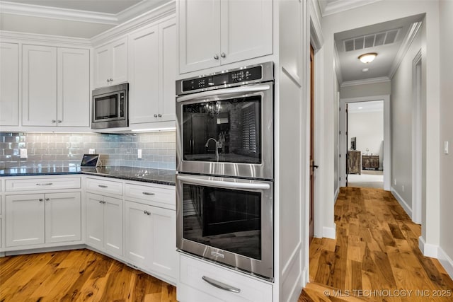 13533 S Lewis Ave, Bixby, OK 74008 - kitchen with stainless steel appliances, crown molding, backsplash, white cabinets, and light wood-style flooring