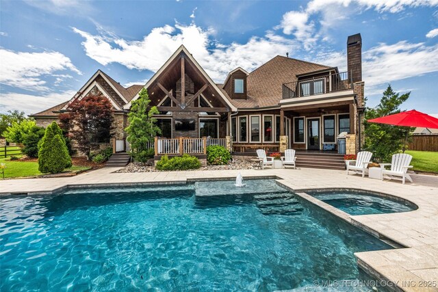 13533 S Lewis Ave, Bixby, OK 74008 - back of house featuring a balcony, a patio area, a pool with connected hot tub, and a chimney