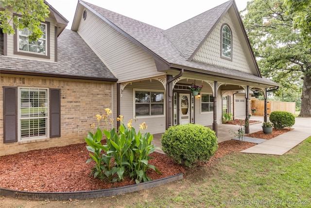 214 Kernel, Durant, OK 74701 - view of front facade featuring a shingled roof, covered porch, brick siding, and a garage