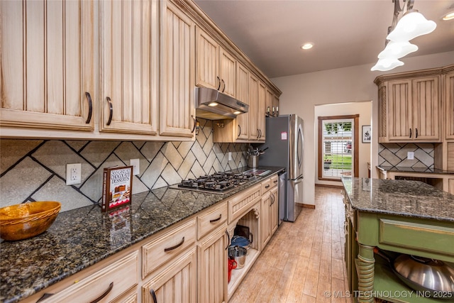214 Kernel, Durant, OK 74701 - kitchen with under cabinet range hood, stainless steel appliances, tasteful backsplash, dark stone counters, and light wood-style floors