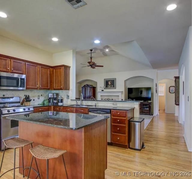 203 E 125th Pl S, Jenks, OK 74037 - kitchen featuring stainless steel appliances, arched walkways, a peninsula, a kitchen island, and open floor plan