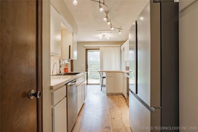 32 SE Shadowlake Dr Unit 32, Bartlesville, OK 74006 - kitchen with freestanding refrigerator, dishwasher, a peninsula, light countertops, and light wood-type flooring