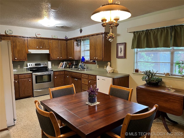 201 NE 18th Ave, Durant, OK 74701 - kitchen featuring white appliances, under cabinet range hood, plenty of natural light, light countertops, and a textured ceiling