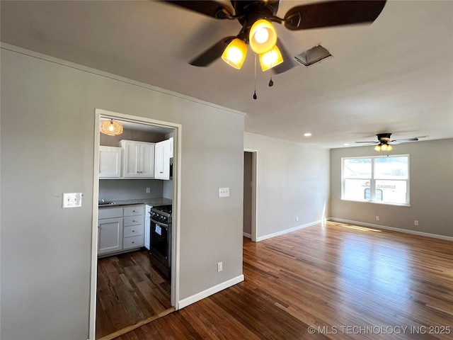 1424 S Penn Ave, Bartlesville, OK 74003 - kitchen with black gas range, a ceiling fan, dark wood-style floors, white cabinets, and open floor plan
