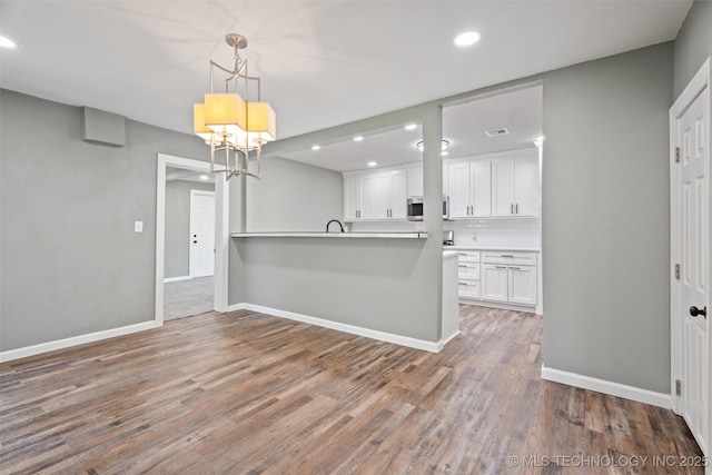 202 N Creek, Dewey, OK 74029 - kitchen with stainless steel microwave, recessed lighting, white cabinets, a peninsula, and a chandelier