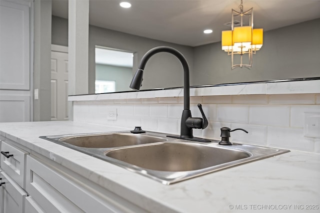 202 N Creek, Dewey, OK 74029 - detailed view of decorative backsplash, recessed lighting, hanging light fixtures, white cabinets, and light stone counters