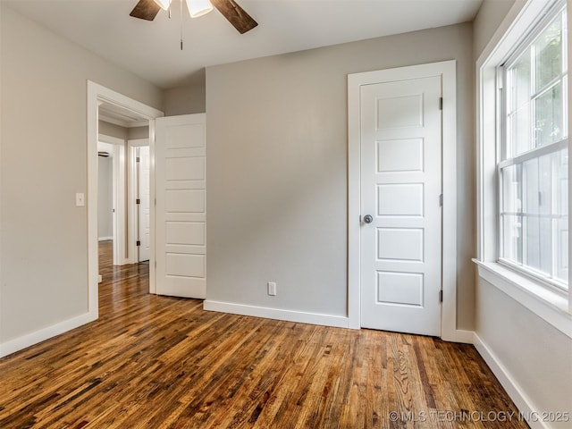 3226 N Garrison Ave, Tulsa, OK 74106 - unfurnished bedroom with dark wood-style floors, multiple windows, and a ceiling fan