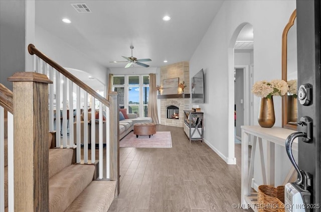 30130 S Maxine Ave, Inola, OK 74036 - entrance foyer with ceiling fan, arched walkways, stairway, light wood finished floors, and a fireplace