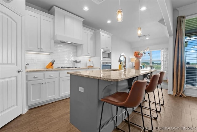 30130 S Maxine Ave, Inola, OK 74036 - kitchen featuring appliances with stainless steel finishes, recessed lighting, white cabinets, a kitchen island with sink, and wood finished floors