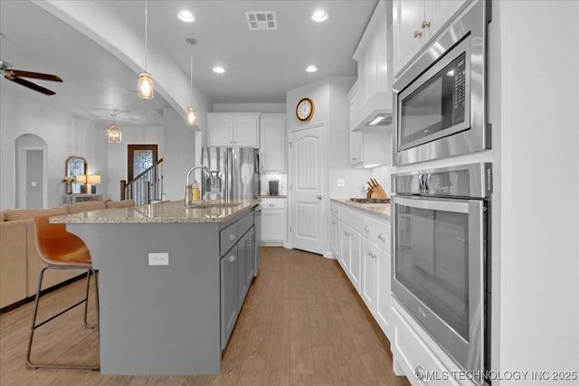 30130 S Maxine Ave, Inola, OK 74036 - kitchen with stainless steel appliances, white cabinets, open floor plan, a breakfast bar, and ceiling fan