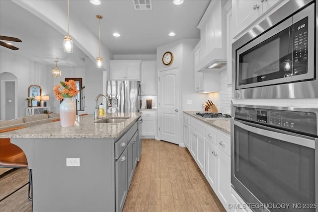 30130 S Maxine Ave, Inola, OK 74036 - kitchen with appliances with stainless steel finishes, decorative backsplash, light wood-style flooring, white cabinets, and a kitchen island with sink