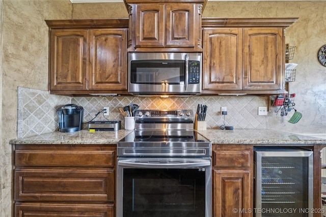 5983 E 137th St, Collinsville, OK 74021 - kitchen with appliances with stainless steel finishes, beverage cooler, tasteful backsplash, light stone counters, and a textured wall