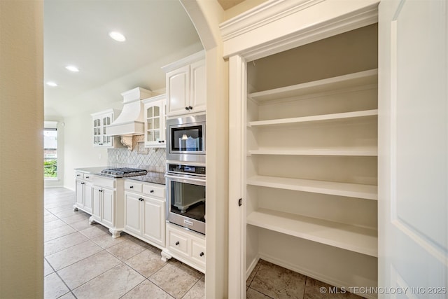 4204 N Maple Pl, Broken Arrow, OK 74012 - kitchen featuring stainless steel appliances, premium range hood, light tile patterned floors, backsplash, and white cabinetry