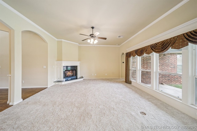 4204 N Maple Pl, Broken Arrow, OK 74012 - unfurnished living room with arched walkways, a ceiling fan, carpet flooring, ornamental molding, and a warm lit fireplace