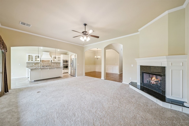 4204 N Maple Pl, Broken Arrow, OK 74012 - unfurnished living room with light colored carpet, arched walkways, a ceiling fan, crown molding, and a fireplace