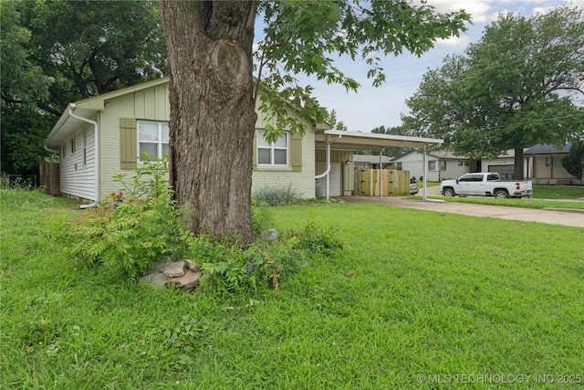 5718 E 27th St, Tulsa, OK 74114 - view of front of house with a carport, concrete driveway, a front yard, and brick siding