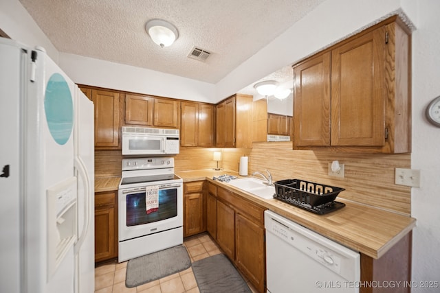 1234 S 110th E Ave Unit 59-4A, Tulsa, OK 74128 - kitchen with white appliances, a textured ceiling, decorative backsplash, brown cabinets, and light tile patterned floors