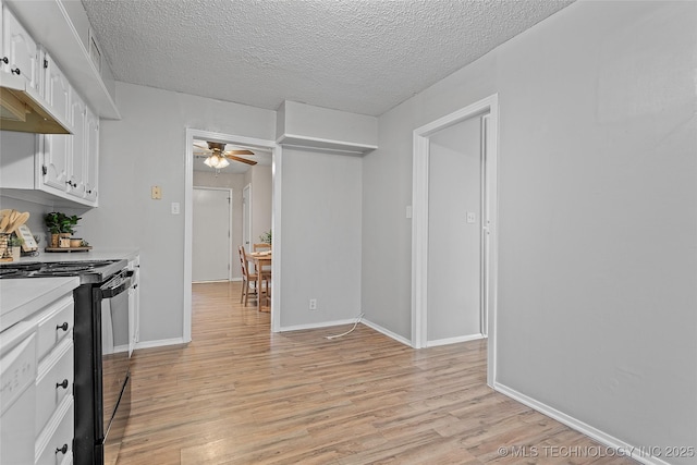 1015 NW Maxwell, Ardmore, OK 73401 - kitchen with black range with electric stovetop, ceiling fan, light countertops, white cabinets, and light wood-style flooring