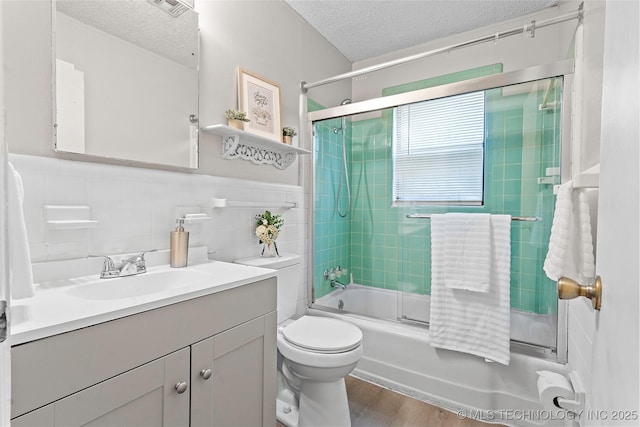 1015 NW Maxwell, Ardmore, OK 73401 - bathroom with a textured ceiling, vanity, enclosed tub / shower combo, wood finished floors, and tile walls