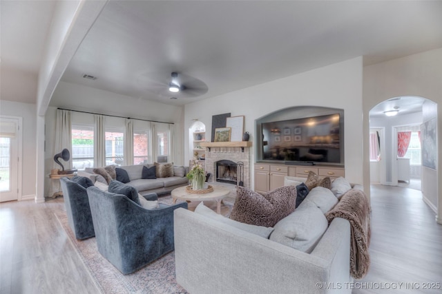 7349 E 119th Pl S, Bixby, OK 74008 - living area featuring light wood-style floors, a ceiling fan, a fireplace, and arched walkways