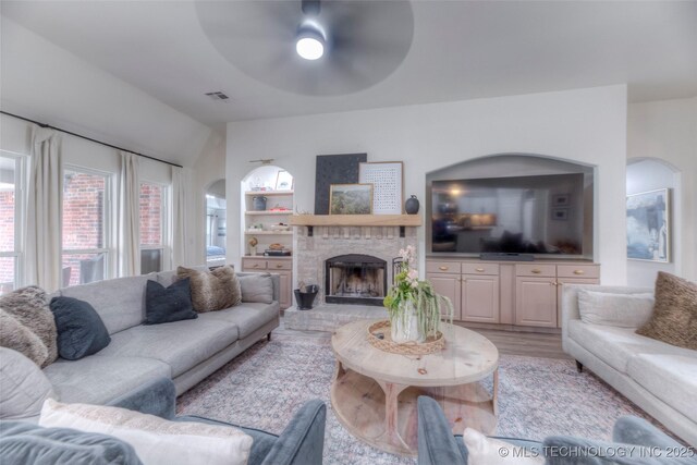 7349 E 119th Pl S, Bixby, OK 74008 - living area with a ceiling fan, light wood finished floors, a fireplace with raised hearth, arched walkways, and built in features