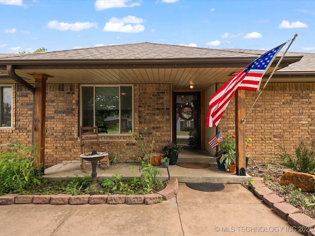 105 Quail Creek Ln, Skiatook, OK 74070 - property entrance with brick siding, covered porch, and roof with shingles