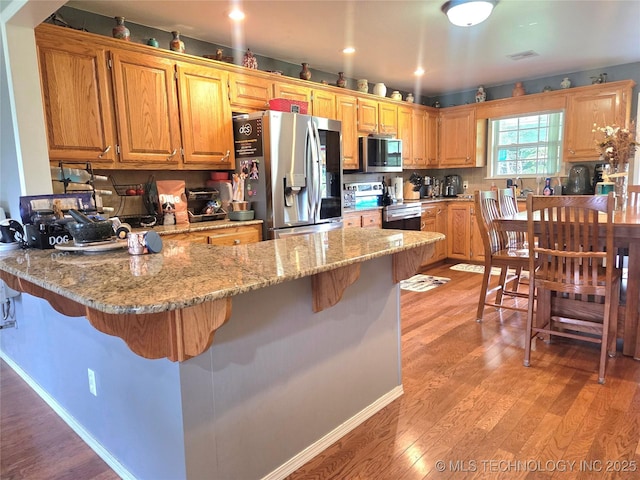 76654 S 4695, Stilwell, OK 74960 - kitchen with stainless steel appliances, a peninsula, a kitchen bar, light wood-style floors, and recessed lighting
