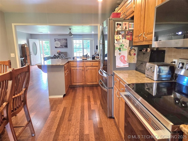 76654 S 4695, Stilwell, OK 74960 - kitchen with stainless steel appliances, dark wood finished floors, brown cabinetry, and a peninsula