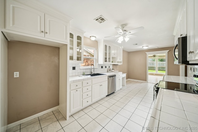 106 E 21st St, Owasso, OK 74055 - kitchen featuring tile counters, stainless steel appliances, ceiling fan, tasteful backsplash, and glass insert cabinets