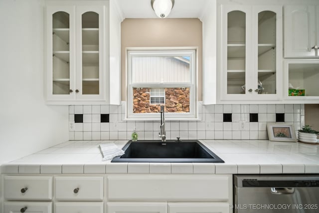 106 E 21st St, Owasso, OK 74055 - kitchen with stainless steel dishwasher, white cabinets, decorative backsplash, light countertops, and glass insert cabinets