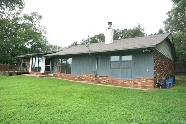 710 N 14th St, Henryetta, OK 74437 - back of property with brick siding, a chimney, a yard, a wooden deck, and roof with shingles