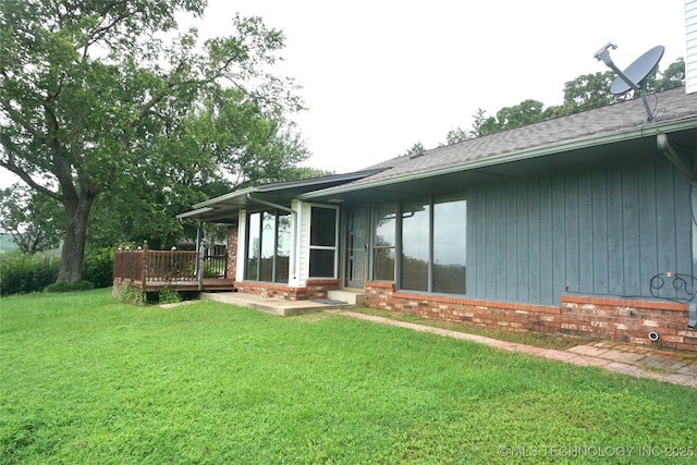 710 N 14th St, Henryetta, OK 74437 - rear view of house featuring a wooden deck, a lawn, brick siding, and a sunroom