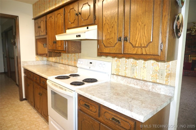 710 N 14th St, Henryetta, OK 74437 - kitchen featuring white electric range, under cabinet range hood, light countertops, tasteful backsplash, and brown cabinetry