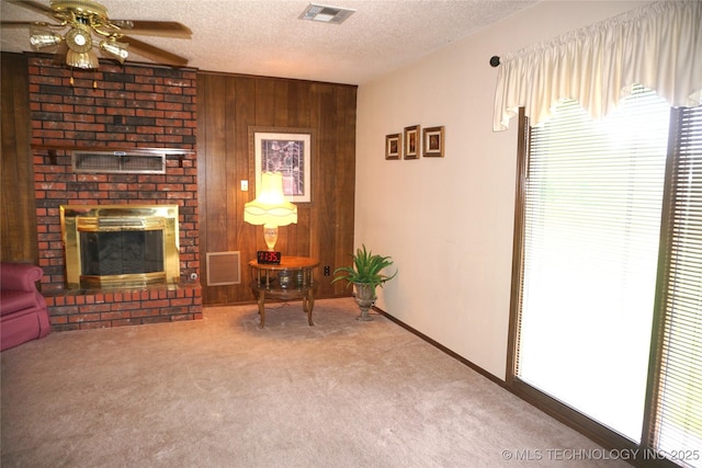 710 N 14th St, Henryetta, OK 74437 - living area with healthy amount of natural light, wood walls, carpet flooring, ceiling fan, and a fireplace
