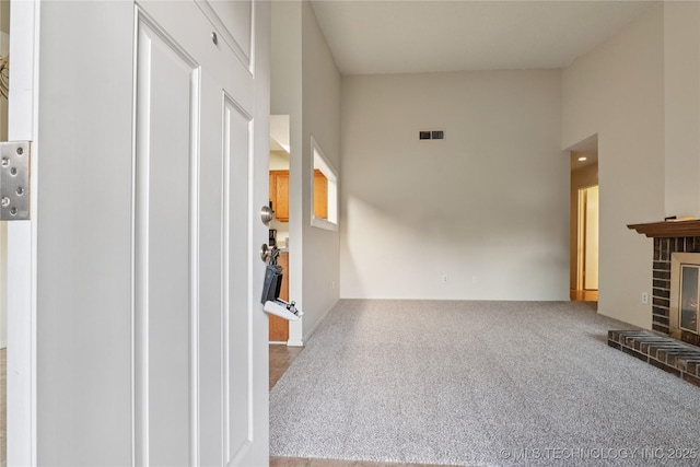 11030 E 11th Pl Unit 4A, Tulsa, OK 74128 - unfurnished living room featuring carpet, a towering ceiling, and a brick fireplace
