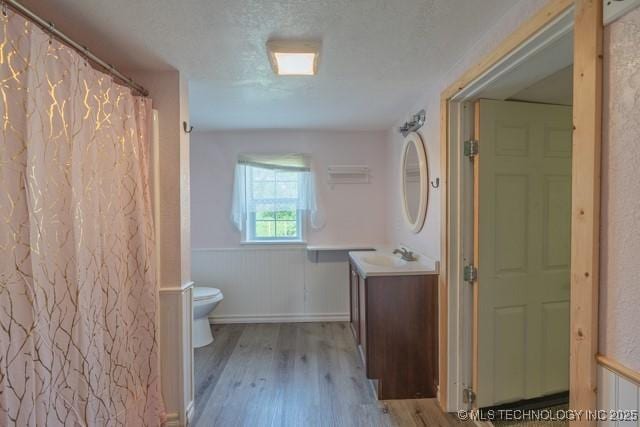 604 N N W, Konawa, OK 74849 - bathroom featuring vanity, wood finished floors, wainscoting, a shower with curtain, and a textured ceiling