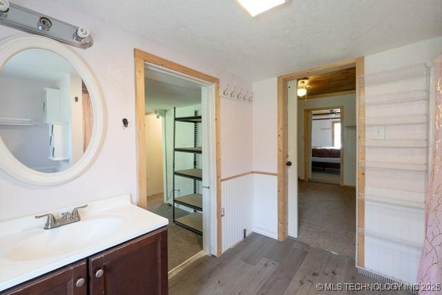 604 N N W, Konawa, OK 74849 - bathroom with wood finished floors, vanity, and a textured ceiling